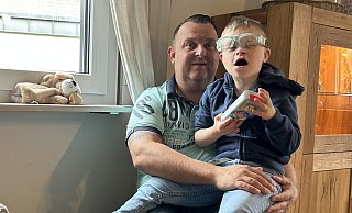 Die Brille von Louis ist etwas verrutscht, als er auf Papas Schoß krabbelt. Gemeinsam sitzen sie in der Spielecke des Wohnzimmers. Der Zehnjährige hält sein liebstes Musikspielzeug in den Händen. - Anna-Lena Hinder