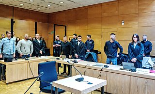 Die vier Angeklagten sollen gegenüber ihrem Opfer angegeben haben, zu den Bandidos zu gehören. Zum Prozessauftakt stehen sie im Gerichtssaal mit ihren Anwälten sowie einem Dolmetscher (ganz links). - Barbara Franke