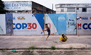 Ein Junge kickt einen Fußball in der Nähe der Beschilderung für die UN-Klimakonferenz COP30 in Belem, Brasilien. - Jorge Saenz/AP/dpa