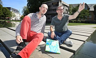 Holger Sauer (l.) hat sein Bild „Jesus mit rosa Lippen" mitgebracht zum Mittagsgespräch mit NW-Kulturchef Stefan Brams. Wegen des schönen Wetters entstand das Foto vorm Holzhaus. - Sarah Jonek