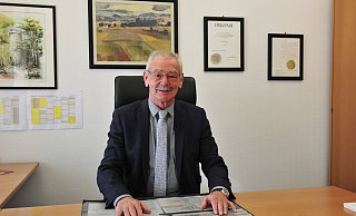 Bürgermeister Ernst-Wilhelm Vortmeyer richtet sich in einer Video-Botschaft von seinem Büro aus an die Einwohner von Rödinghausen. - Gemeinde Rödinghausen