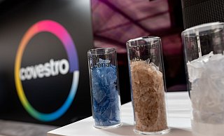 Eine deutsche Firma wird arabisch: Das Logo des Spezialchemie-Konzerns in einem Firmen-Showroom, davor Gläser mit Covestro-Materialien. - Fabian Strauch/dpa