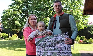 Pia Breimann und Daniel Pohlmann zeigen mit ihrem 14 Monate alten Sohn Luis auf einem Plan, dass auf der anderen Seite des Burgwegs in zweiter Reihe Häuser gebaut wurden. - Marion Pokorra-Brockschmidt