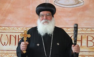 Bischof Anba Damian in traditioneller Bischofskleidung mit Seidenhut, Bischofsstab aus Ebenholz sowie Leder- und Holzkreuz im renovierten Speisesaal des Klosters. Foto: Alexander Graßhoff - Alexander Graßhoff