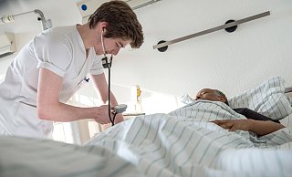 Ein Krankenpflegeschüler misst den Blutdruck eines Patienten. - epd