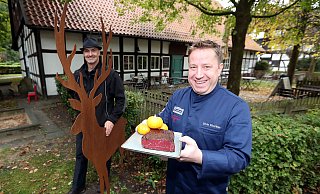 Kunst und Küche: Der Hirsch mit mächtigem Geweih wacht über den Historische Gasthof Buschkamp, in dem Gastronom Silvio Eberlein (rechts) auch Allerlei aus Wildtierfleisch zubereitet. Die Wildtierfiguren auf dem Hofgelände stammen vom Verler Stahlkünstler Hans Kordes. - Wolfgang Rudolf