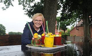 Auch bei Regen ist die bunte Deko auf dem Tisch der Sitzgruppe an der Varler Friedenseiche ein Blickfang. Über die als Cocktails gestaltete Deko im Dorf freut sich auch Ortsvorsteherin Anette Streich. - Joern Spreen-Ledebur