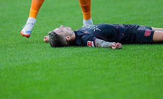 Bayer Leverkusens Kapitän Alejandro Grimaldo liegt nach einem Zusammenprall mit dem eigenen Mann benommen auf dem Boden. - Rolf Vennenbernd/dpa