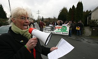 Während Marion Schröder (l.) ihren Unmut deutlich macht, formieren sich im Hintergrund die ersten Demonstranten mit Plakaten. - Foto: Peter Steinert