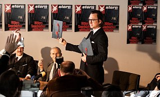 Pressekonferenz in der Stern-Redaktion: Gerd Heidemann (Lars Eidinger) präsentiert die Hitler Tagebücher und liest aus ihnen vor. - RTL / Martin Valentin Menke