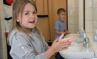Isabella und Jules waschen sich die Hände und singen dabei zweimal hintereinander „Happy Birthday". So können sie einschätzen, wie lange das Waschen dauern soll, um wirksam zu sein. - Britta Bohnenkamp-Schmidt