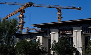 Baukräne stehen in der Nähe eines Bürogebäudes des Evergrande New Housing Development Showroom. - Foto: Andy Wong/AP/dpa