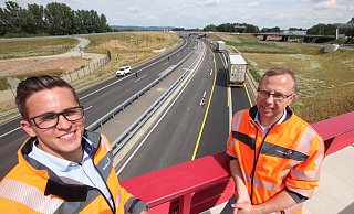 Projektleiter Florian Fawick (l.) und Bauabteilungsleiter Tobias Fischer von Straßen NRW im Löhner Kreuz, dem letzten Bauabschnitt der Nordumgehung. Hinter ihnen ist noch die Baustellenführung auf der neuen Autobahn mit den gelben Fahrbahnmarkierungen zu sehen. - Jörg Stuke