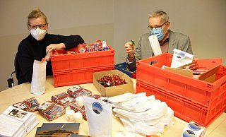 Gemeindereferentin Christina Bolte (l.) und Verwaltungsleiter Martin Hünemeyer füllen Kisten mit den Inhalten der „Weihnachtstüten“. 1.800 Stück werden in den Warburger katholischen Gemeinden gepackt und sollen zu den Festtagen die Menschen erreichen. - Dieter Scholz