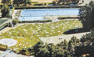 Blick von oben: Ein Sommer in den 1970er Jahren: Das Freibad in Ennigloh ist gut besucht. Auf der Wiese und im Wasser tummeln sich Menschen. Nur der Parkplatz ist noch nicht ganz so voll, wie er es vermutlich heute wäre. - Picasa