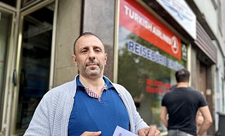 Ein geprellter Kunde steht vor dem geschlossenen Reisebüro in Bielefeld und zeigt seinen wertlosen Buchungsbeleg. - Stefan Becker