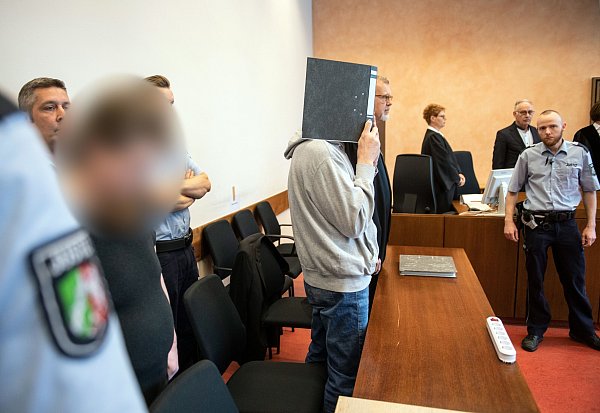 Die Angeklagten Mario S. (l) und Andreas V. (mit Aktenordner) stehen im Gerichtssaal des Landgerichts nebeneinander. Die beiden Angeklagten sollen über Jahre auf einem Campingplatz in Lügde hundertfach Kinder sexuell missbraucht und dabei gefilmt haben. - © Verwendung weltweit