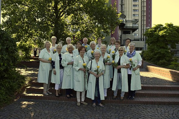 Die Grünen Damen und ein Grüner Herr stehen in ihren typischen lindgrünen Kitteln vor dem Klinikum Bielefeld. - © Klinikum Bielefeld
