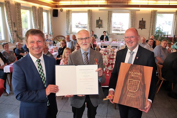 Josef Köhne (Mitte) bekommt im Auftrag des Bundespräsidenten Frank-Walter Steinmeier das Bundesverdienstkreuz aus den Handen des Landrats Michael Stickeln (l.). Nieheims Bürgermeister Johannes Schlütz lädt den Geehrten ein, sich auch ins "Goldene" Holzbuch der Stadt einzutragen. - © David Schellenberg
