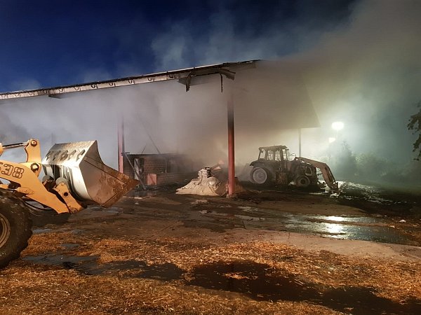 Nächtlicher Einsatz: In der Dunkelheit wurde die Brandstelle ausgeleuchtet. Mit Radladern holten Landwirte das brennende Stroh aus der Halle. - © Andreas Berg