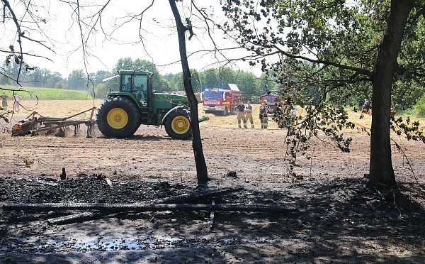 Zur Sicherheit wird das Feld gegrubbert, im Vordergrund verkohlte Reste des Unterholzes. - © Feuerwehr Ostenland