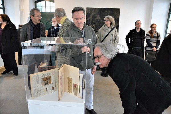 Die Besucher schauen interessiert in die Glasvitrinen. In ihnen sind Tage- und Malbücher von Jürgen Heinrich zu sehen. - © Karin Prignitz