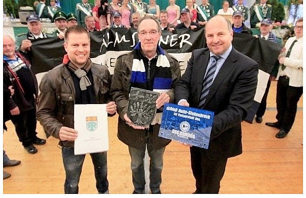 Zum Zeichen der Freundschaft hat Bürgermeister Hubert Erichlandwehr (r.) von Hans-Jürgen Laufer ein Schild fürs Rathaus bekommen, der DSC-Vizepräsident hält ein gusseisernes SHS-Wappen, das gedruckt auch auf dem Titelblatt des Kooperationsvertrages prangt, den Arminia-Marketing-Beauftragter Finn Holsing hält. Im Hintergrund die Almsenner mit ihrem Banner und ganz hinten der Thron der St.-Achatius-Schützenbruderschaft. - © FOTO: SABINE KUBENDORFF