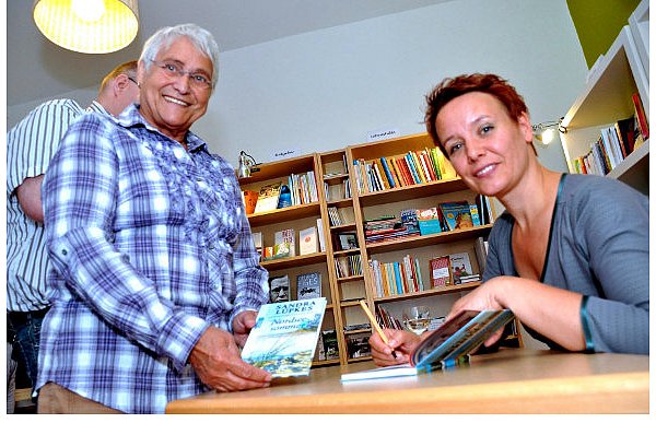 Sandra Lüpkes hat in Helpup nicht aus einem ihrer Kriminalromane gelesen, sondern aus der Erzählung "Nordseesommer", die im April erschienen ist. Christa Pott lässt sich das Buch von der Autorin signieren. - © FOTO: KARIN PRIGNITZ