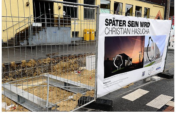 Die Apfelbaum-Skulptur soll auf die beiden Stahlträger montiert werden, die auf den beiden Fundamanentblöcken im Untergrund des Bahnhofsvorplatzes ruhen. Ein Transparant am Bauzaun zeigt Modelle der Skulptur (mit dem geplanten Bahnhofsneubau) und nennt das Thema der Arbeit Christian Hasuchas. - © FOTO: MARC KÖPPELMANN