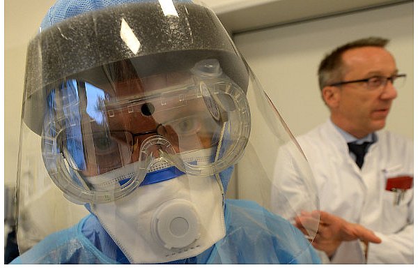 Diese Kleidung müssen alle Mitarbeiter tragen, die mit Ebola-Patienten in Kontakt kommen. Hygienefachkraft Barbara Klesse zeigt den Schutzanzug, im Hintergrund beobachtet von Chefarzt Gero Massenkeil. - © Foto: Raimund Vornbäumen