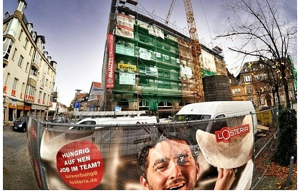 Das Brandhaus soll nach seiner Fertigstellung zum Stil des Ratsgymnasiums (r.) und dem Gebäude auf der linken Seite passen. Am Bauzaun Werbung für die L'Osteria. Das italienische Restaurant wird voraussichtlich im Februar eröffnet. - © FOTO: ANDREAS FRÜCHT