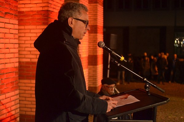 Hinterfragt Verschwörungstheorien: Ingo Grabowsky spricht im Schatten des illuminierten Mahnmals zu den Anwesenden. - © Dietmar Gröbing