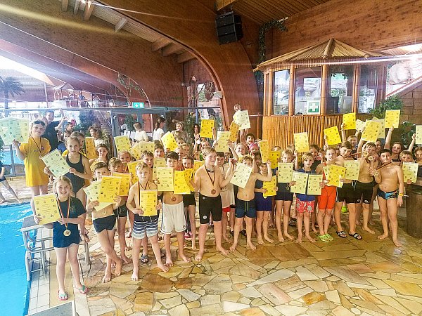 Siegerehrung I: Stolz halten die erfolgreichen schwimmenden Grundschüler ihre Urkunden hoch. Um den Hals tragen sie ihre Medaillen. - © Yvonne Gottschlich