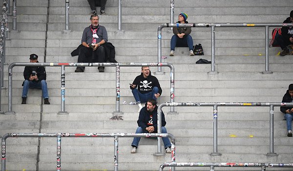 Fans des FC St. Pauli sitzen mit Abstand auf der Stehtribüne am Millerntor. Mit dem ursprünglichen Stadionerlebnis habe das für viele nichts zu tun, sagt ein Fanforscher. - © picture alliance/dpa
