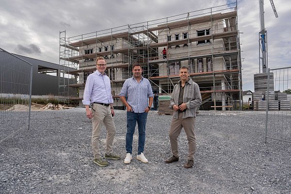 Michael Kubat (v. l.), Daniel Fingerhut (Geschäftsführer FMK-Steuerberatungsgesellschaft) und Bürgermeister Burkhard Schwuchow stehen vor dem im Bau befindlichen Bürogebäude. - © Michael Kirchner