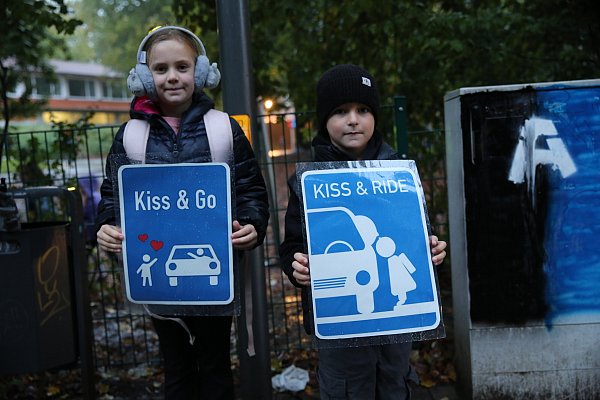 Die Grundschülerin Lu und ihr Mitschüler Nika zeigen die beiden Schilder, mit denen für so genannte "Kiss & Go" sowie "Kiss & Ride" - Zonen geworben wird. - © Elke Niedringhaus-Haasper