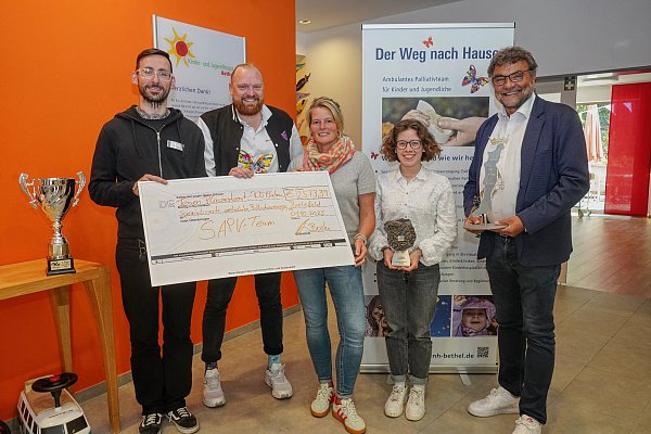 René Meistrell (li.) und Tanja Gresing (3. v. li.) freuen sich im Namen des Palliativteams "Der Weg nach Hause" über eine Spendensumme von 2573,39 Euro, die das Radsportteam Plasmatreat-RTS Electronic während der Saison gesammelt hat. Den Scheck überreichten Teamchef David Buske (2. v. li.), Bundesliga-Radsportlerin Anna Scheffler und Plasmatreat-Firmenchef Christian Buske (re.) --- Radsport Saison 2025 Foto vom 1. Oktober 2025 in Bielefeld-Bethel - © Feicht