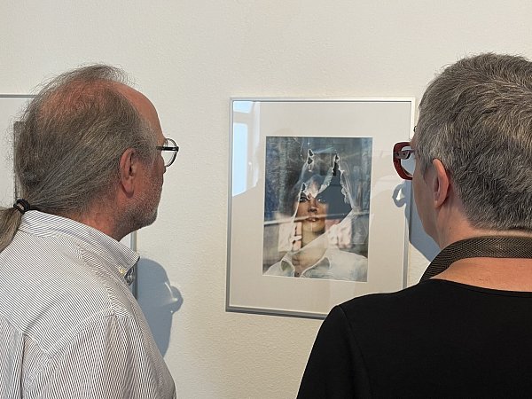 Dagmar Venus (r.) und Heiko Nowak (l.) stehen vor Venus' Werk. Es ist eine Fensterpuppe, die durch eine zerrissene Plastikfolie schaut. - © Verena Freiberg