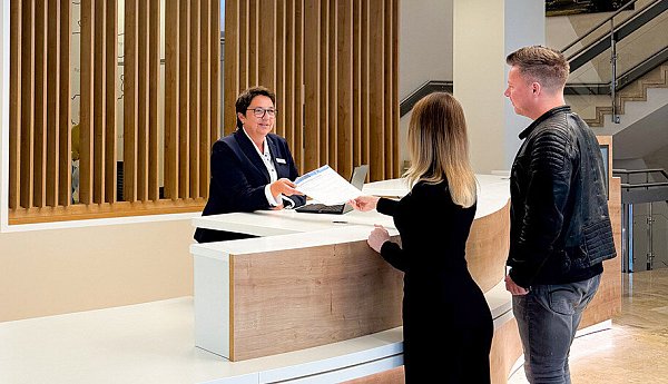 Tanja Berg (hinter dem Counter), Mitarbeiterin des ServiceCenters der Kreisverwaltung, ist mit ihren Kolleginnen und Kollegen im Einsatz und berät Kundinnen und Kunden der Kreisverwaltung. - © Kreis Paderborn