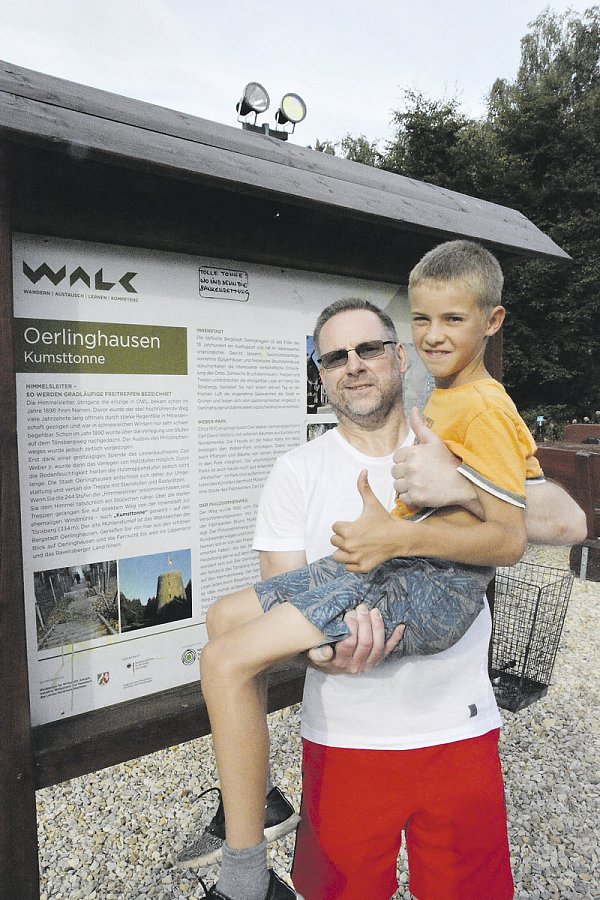 Angekommen: Nach dem schweißtreibenden Aufstieg hat Volker Rethmeier sogar noch die Kraft, den zehnjährigen Hendrik, der zusammen mit ihm die Stufen gezählt hat, hochzuheben. Hinter ihnen steht das Informationsschild, auf dem die Zahl 244 angegeben ist, es sind aber zehn Stufen weniger. - © Karin Prignitz