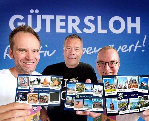 Die Gütersloher Lokalkabarettisten Andreas Neuhaus (von links), Jan Furtwängler und Matthias Borner von "Vox Rindvieh" werben für ihre Show zum 200-jährigen Stadtjubiläum mit Gag-Postkarten. - © Andreas Frücht