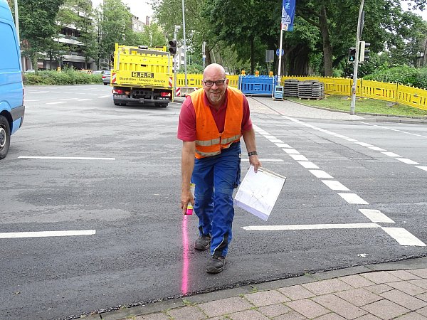 Mit Spaß bei der Arbeit: Markus Eckhardt markiert mithilfe einer Sprühdose mit pinker Farbe den Bereich, unter dem die Versorgungsleitungen liegen. - © Kristina Grube