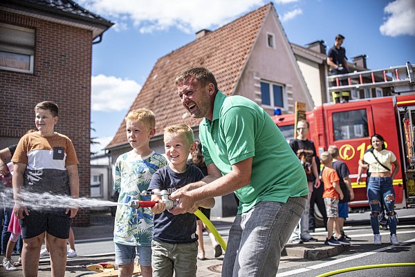 Julian (7) und Fabian (5) dürfen zusammen mit Papa Philipp das Strahlrohr der Feuerwehr ausprobieren. Der Andrang bei dem warmen Wetter an den Wasserschlauch zu kommen ist groß. - © Felix Boche