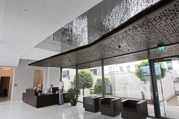 Lichtdurchflutetes Foyer: Decken- und Wandverkleidungen spielen mit der Anmutung von Schokolade und ihrer Stanniol-Verpackung. - © Frank-Michael Kiel-Steinkamp