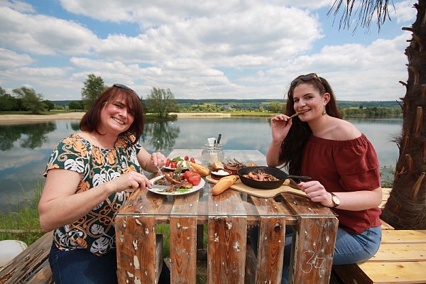 Mediterrane Küche: Meeresfrüchte, Lammkoteletts und frisches Baguette mit Aioli passen perfekt zur herrlichen Kulisse. Die beiden Servicekräfte vom Strandgut, Sabine Hartenstein (l.) und Johanna Loges, lassen es sich schmecken. - © Benedikt Schülter