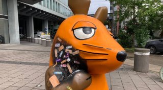 Angebrannte Maus-Figur wird mit Pflastern versorgt