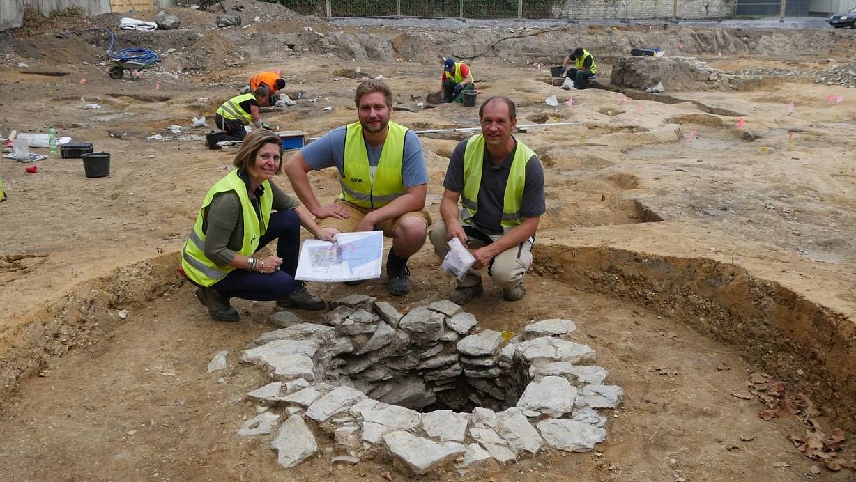 Tiefreichender Fund: Sveva Gai und Till Lodemann von der Stadtarchäologie Paderborn sowie Grabungsleiter Dieter Lammers (v.l.) hinter einem mittelalterlichen Brunnen.  | © Foto: LWL/N. Wolpert