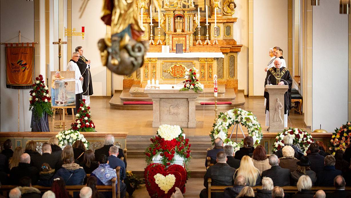 Trauerfeier: Alle Plätze in der St.-Johannes-Baptist-Kirche in Stukenbrock sind besetzt, viele weitere Trauergäste nehmen im Stehen Abschied von Fritz Wurms. Sein mit roten Rosen und Herzen aus weißen Rosen geschmückter weißer Sarg steht in der Mitte. Pfarrer Wolfgang Bender (r.) und Zirkusseelsorger Sascha Ellinghaus (hinten l.) gestalten die Heilige Messe. Fotos: Mike-Dennis Müller | © 2019 Mike-Dennis Müller