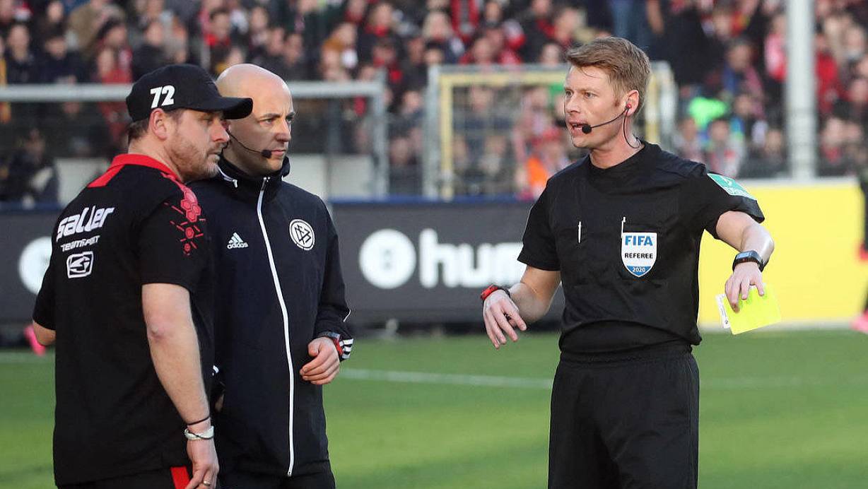 Schiedsrichter Christian Dingert (r.) hat dem Paderborner Trainer Steffen Baumgart gerade die Gelbe Karte gezeigt. Der Hinweis kam vom vierten Offiziellen Nicolas Winter (M.) | © imago images/Sportfoto Rudel