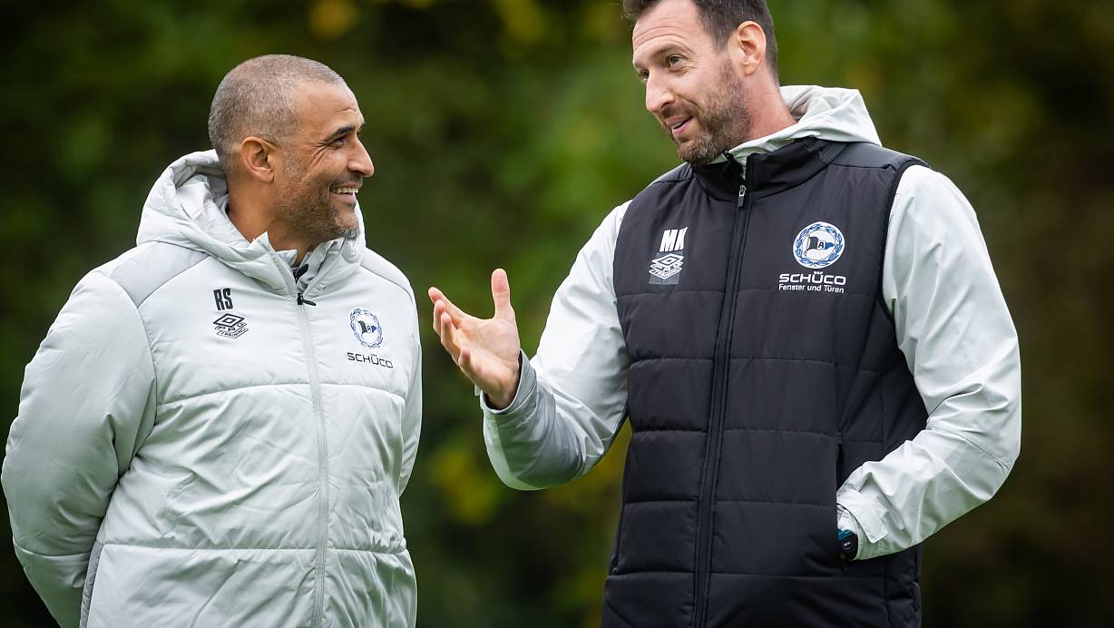 Delron Buckley (l.) holt sich von Arminia-Coach Mitch Kniat wertvolle Tipps für seine Arbeit in Südafrika. Die Jacke hat er sich wegen der Initialen mutmaßlich von Zeugwart Rainer Schonz geliehen. | © Sarah Jonek